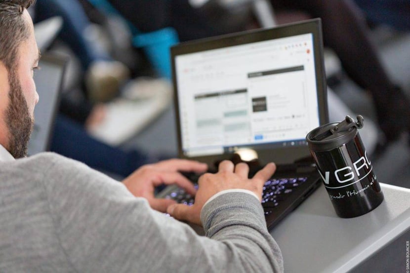 Collaborateur MV Group sur son ordinateur avec tasse MV Group